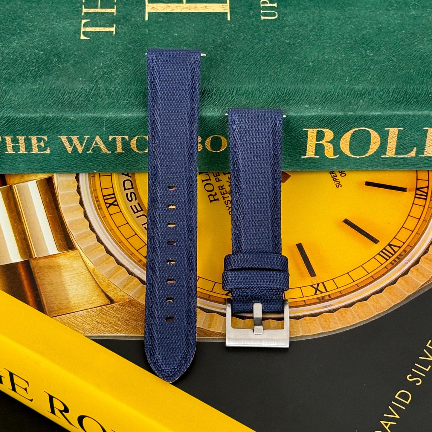 A midnight blue sailcloth watch strap displayed on a surface with a focus on the texture and color, no visible watch.