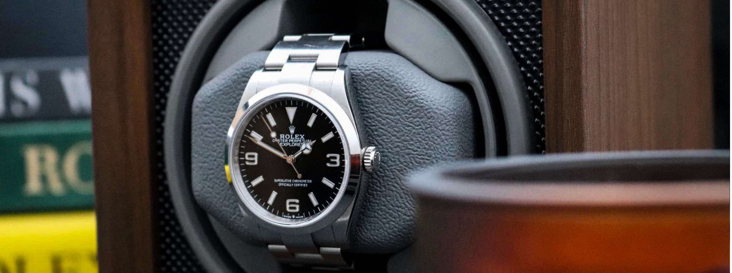 Rolex watch on a wooden watch winder display with books in the background