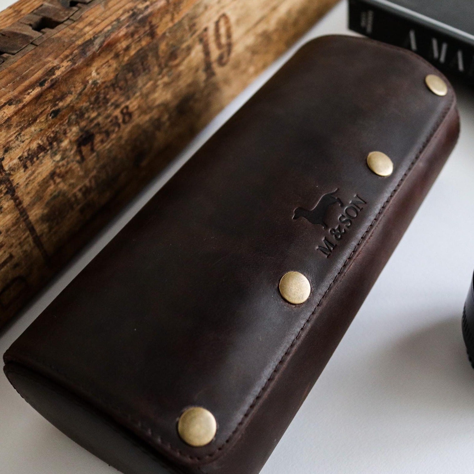 M and Son, triple leather watch roll with embossed logo, side view.