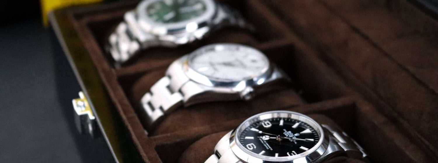 Three silver watches in a wooden display case