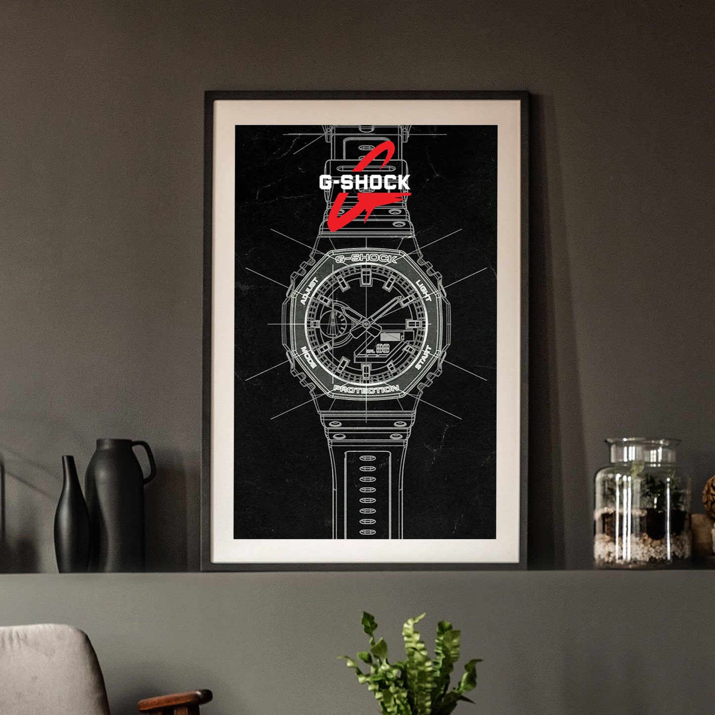 Framed G-Shock watch poster on a wall with decorative items below.
