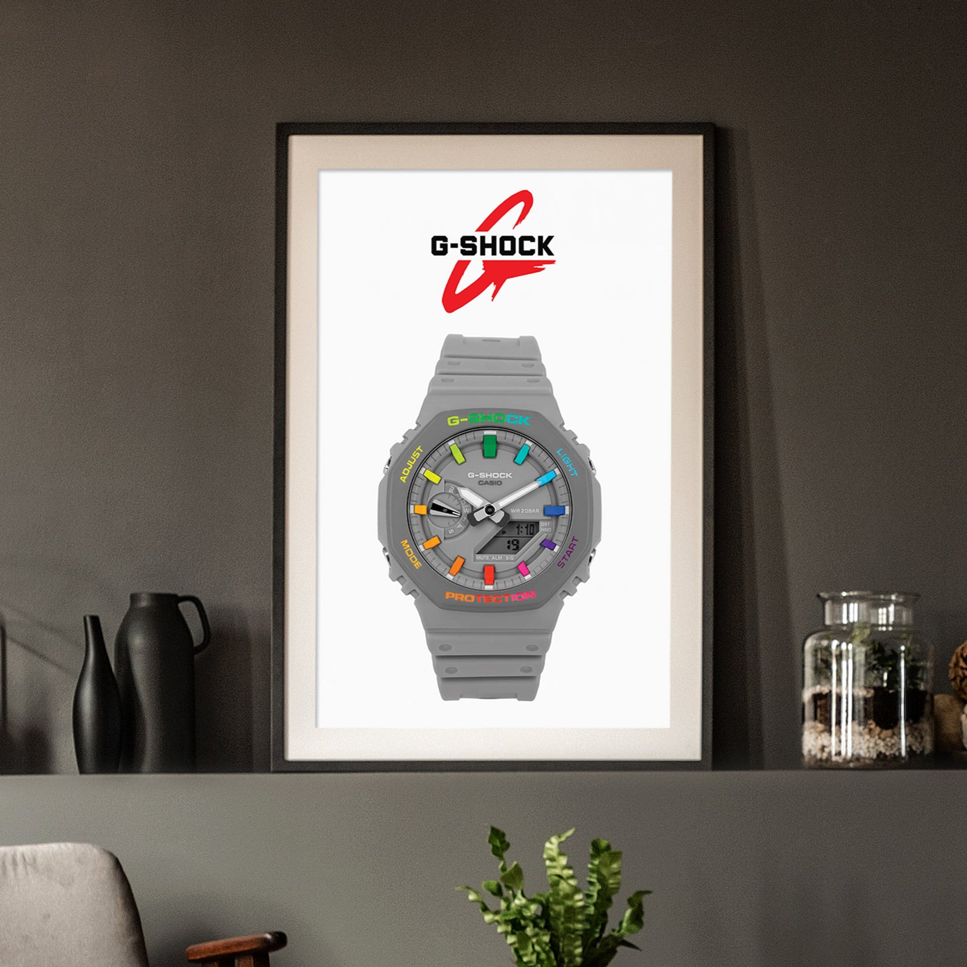 Framed G-Shock watch poster on a wall with decorative items below.