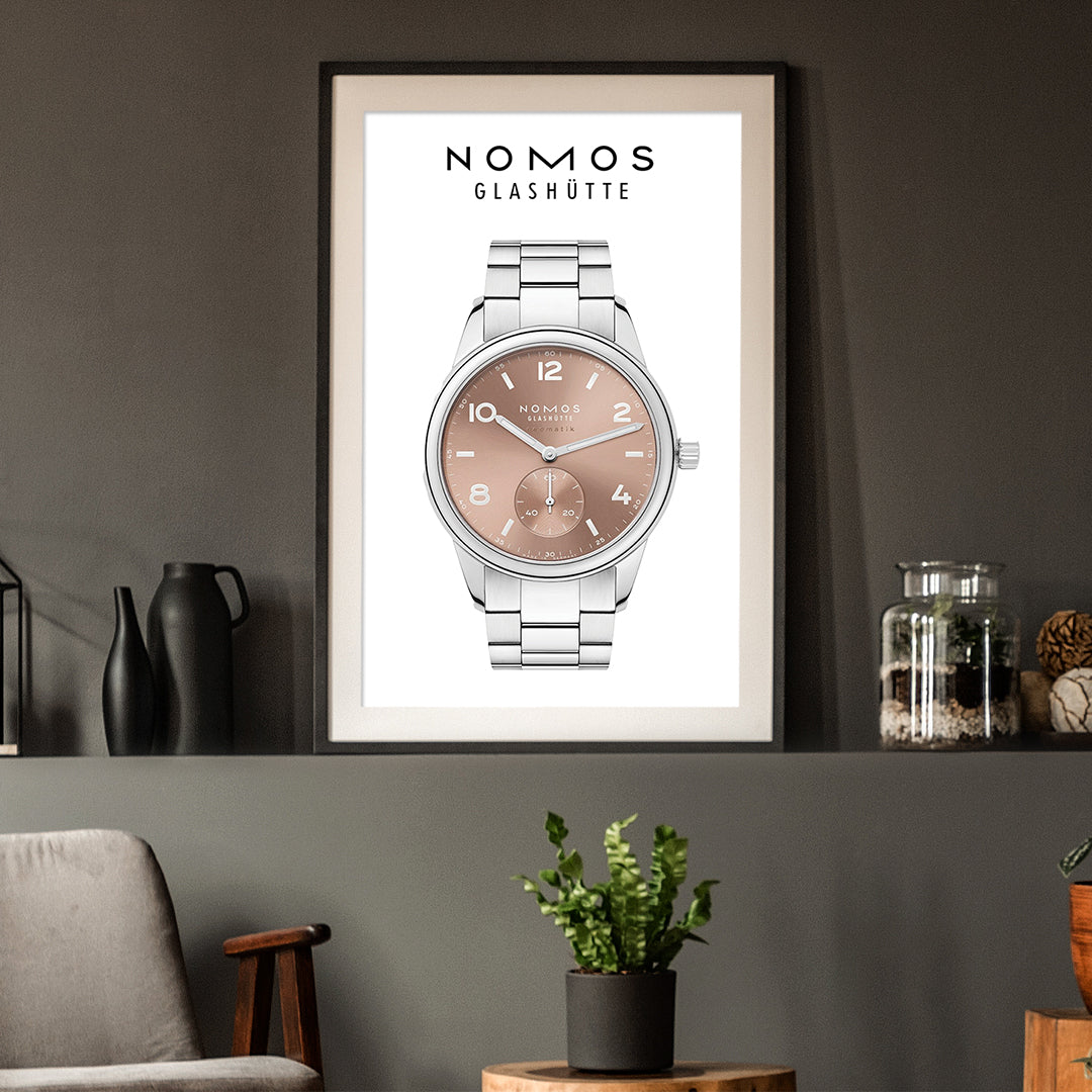 Framed poster of a Nomos Glashütte watch on a wall with decor elements.